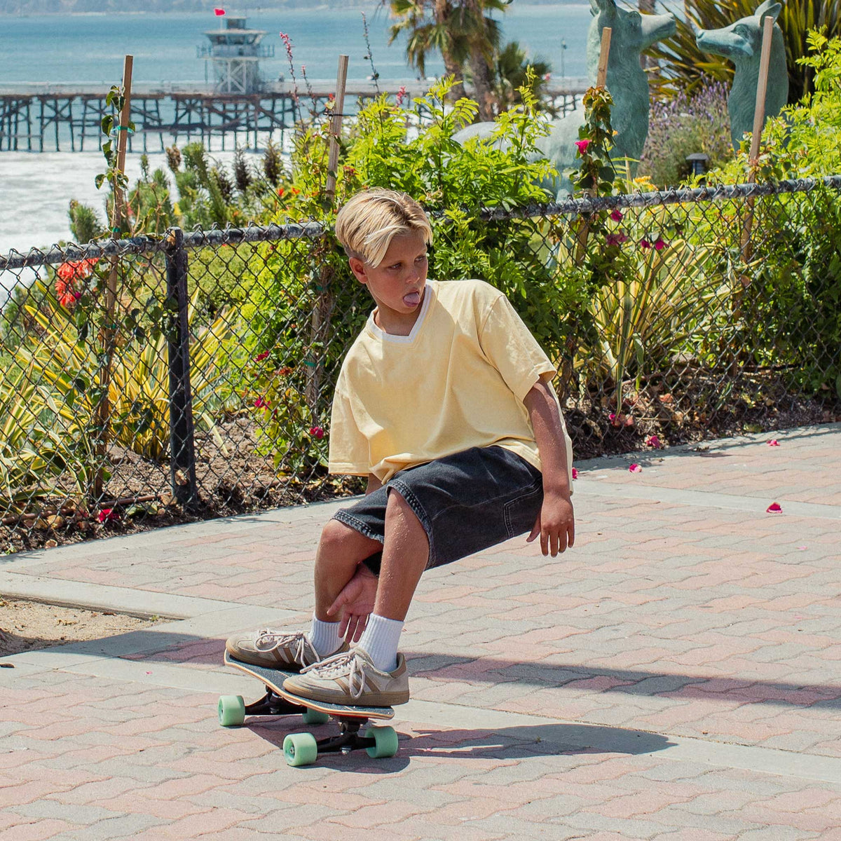 Enfant sur un surfskate Carver Wavy Davy face à la plage