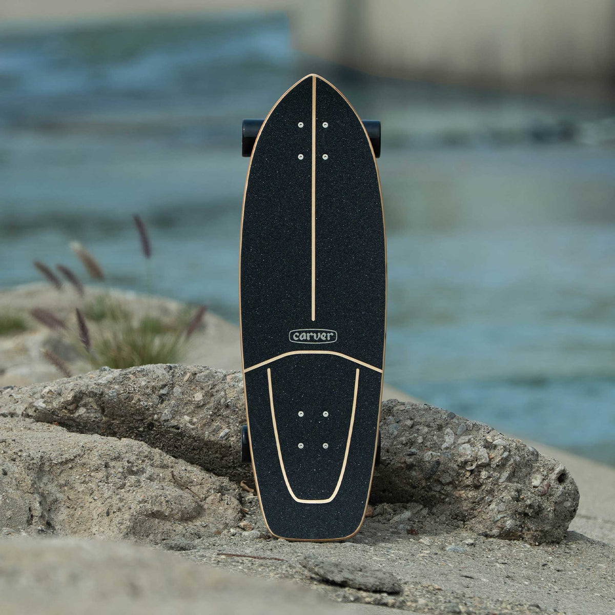 Planche Carver Resin posée sur un rocher au bord de l'eau
